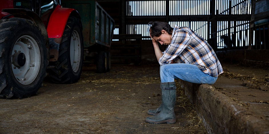 Picture of distressed farmer in shed with tractor